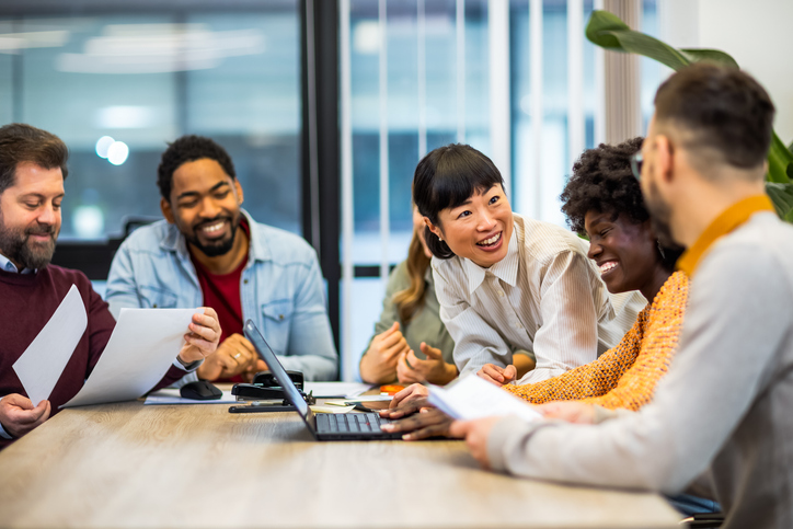 a group of people sitting around the table in a meeting